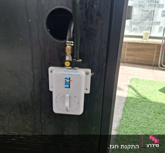 שסתום גז מחובר למכשיר על רקע דשא סינתטי